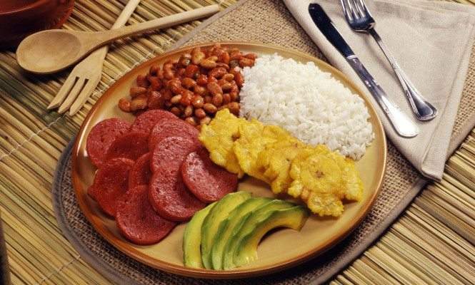 Plato típico dominicano con arroz, frijoles, salami frito, aguacate y tostones (plátanos fritos).